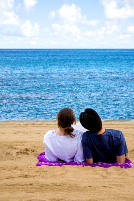 romantic couple relaxing at the beach on a sunny day viewing the horizon