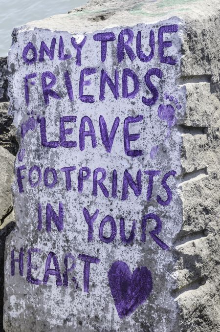Saying by Eleanor Roosevelt painted on breakwall by lake: "Only true friends leave footprints in your heart"