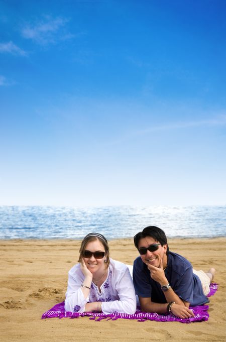 beach couple smiling and relaxing on a sunny day