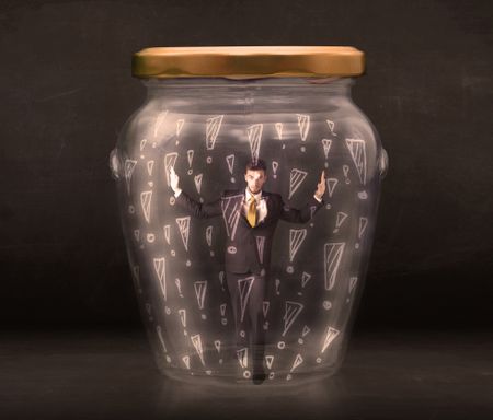 Business man trapped in jar with exclamation marks concept on bakcground