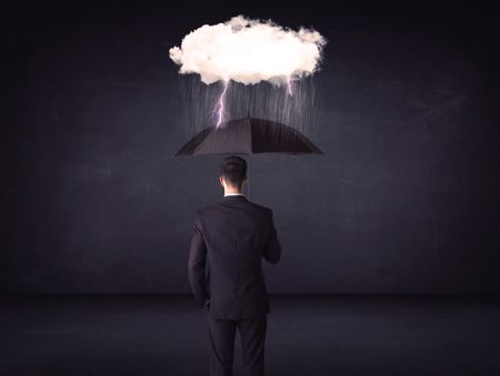 Businessman standing with umbrella and little storm cloud concept on background