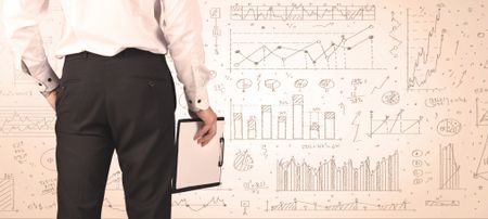 Businessman from the back in front of diagrams and graphs background