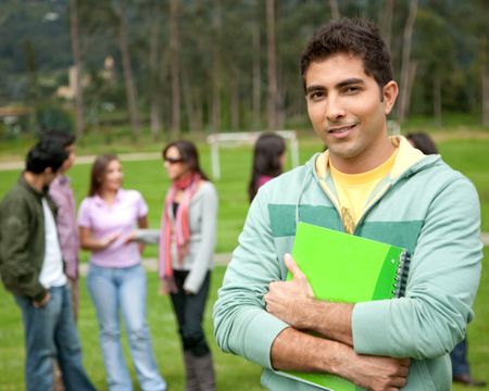 male university student standing outdoors with a notebook