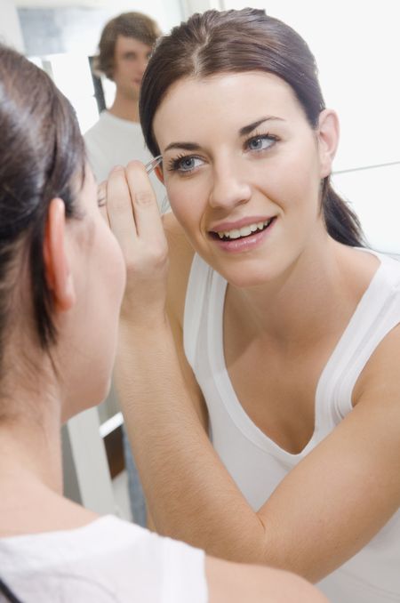Attractive woman plucking eyebrows.