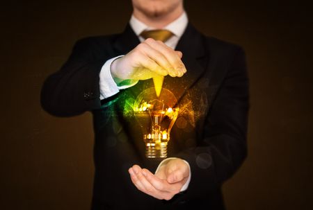 Businessman holding a shining light bulb in front of his body
