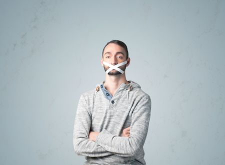 Young man with taped mouth. Isolated on gray background