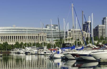 Urban magnetism: Row of yachts docked in Burnham Harbor by Soldier Field, home of the Chicago Bears professional football team, along the lakefront on a sunny spring morning in Chicago