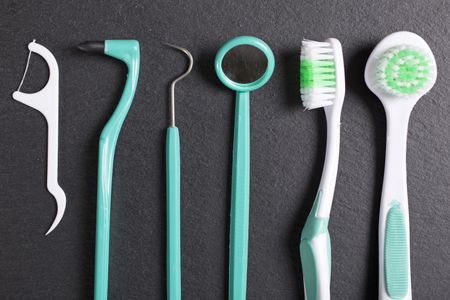 Selection of dentist brushes and tools on a black slate surface