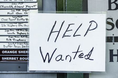 Laminated handwritten "Help Wanted" sign in window of ice cream and yogurt shop in tourist town