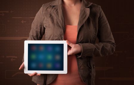 Young woman holding a white tablet with blurry apps