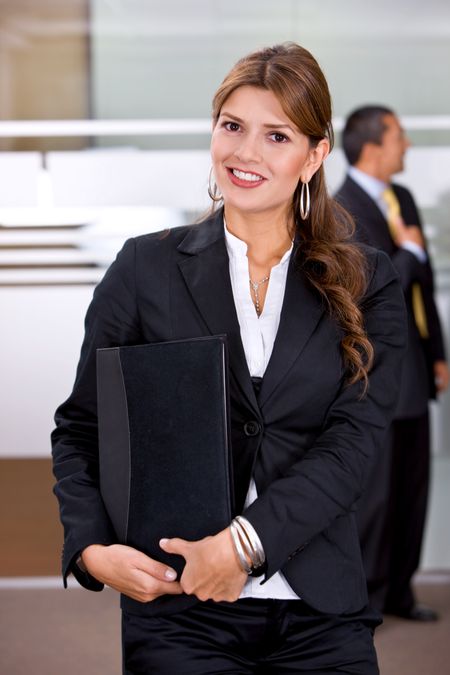 Business woman standing at an office holding a portfolio