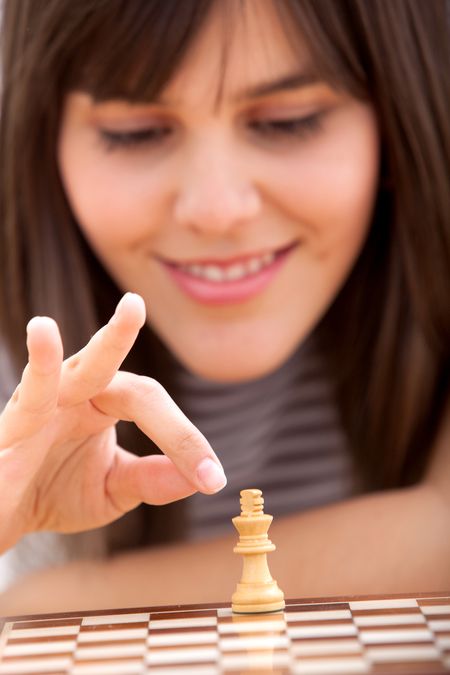 Girl moving a counter while playing chess