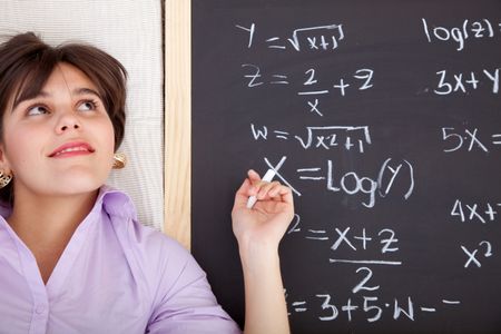 Beautiful girl writing math equations on a chalkboard