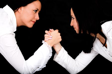 business women arm wrestling over a black background