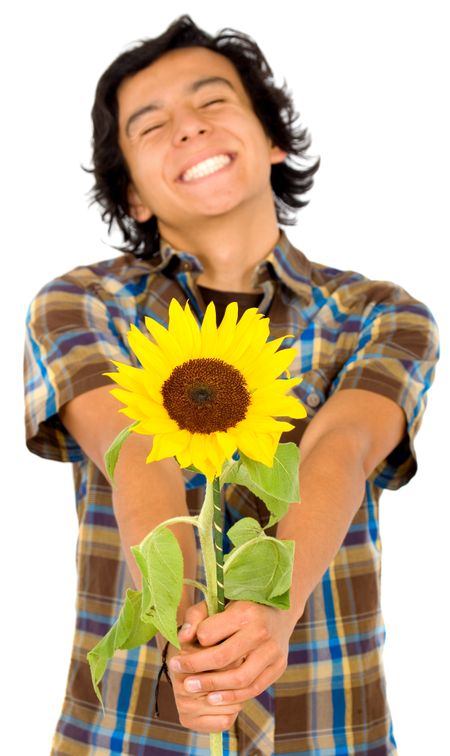 Casual happy man with a big smile handing out a sunflower – isolated over a white background with focus on the flower