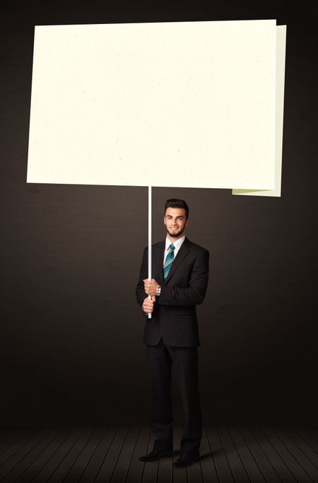 Young businessman holding a big, white post-it paper 