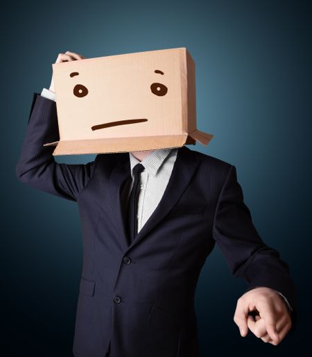 Businessman standing and gesturing with a cardboard box on his head with straight face