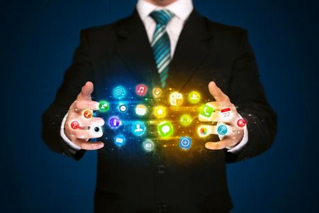 Businessman holding a shining app icon cloud in front of his body

