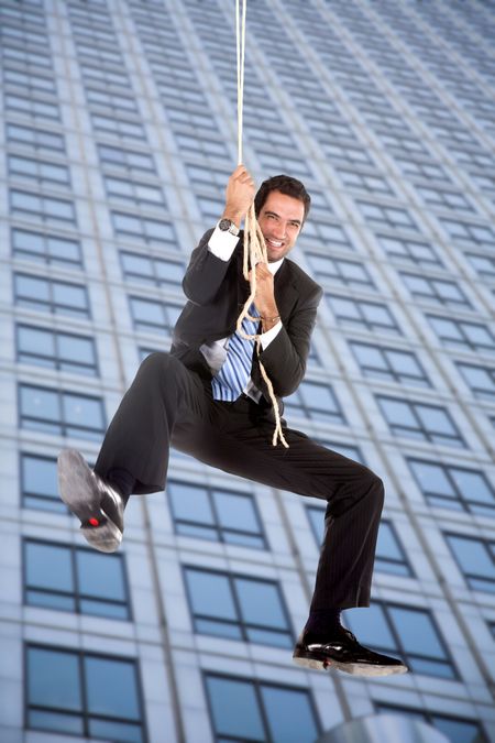 Business man jumping from a building with a rope