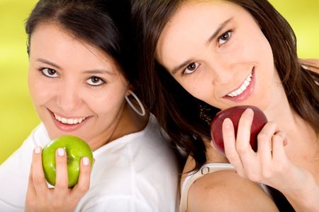 healthy girls on a fruit diet holding apples on their hands over a light green background