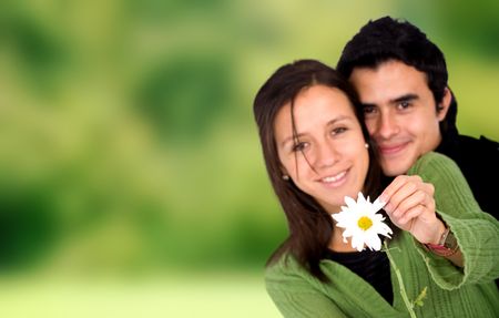 couple in love with a daisy flower outdoors in a park with a green background