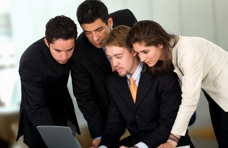 Business team in an office environment all wokring on a laptop computer
