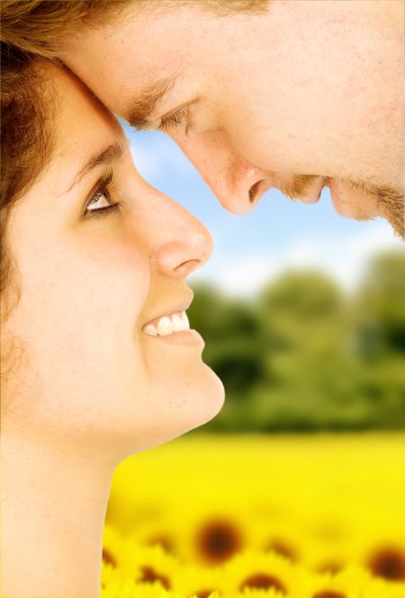 couple of lovers in love face to face outdoors with a field of sunflowers in the background