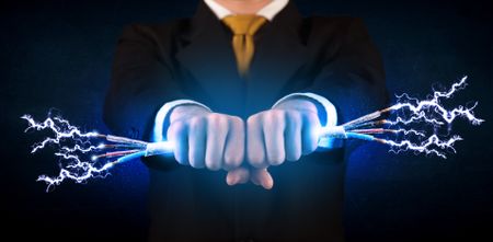 Business person holding electrical powered wires concept on background