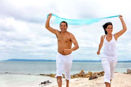 Loving couple running at the beach with a sarong