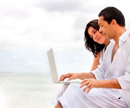 Couple outdoors at the beach with a laptop