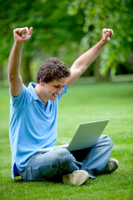 Excited man with a laptop computer outdoors