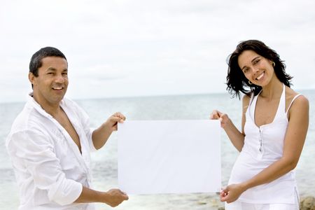 Couple at the beach with a banner smiling