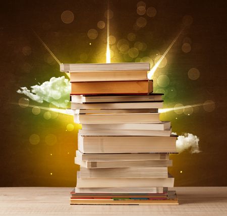 Magical books with ray of lights and colorful clouds on vintage background
