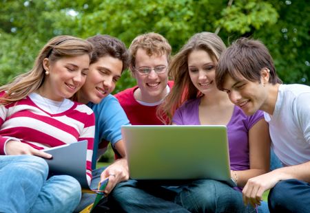 Group of friends with a laptop outdoors and smiling