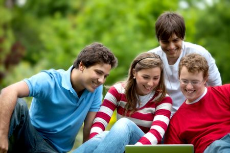 Group of students smiling with a computer outdoors