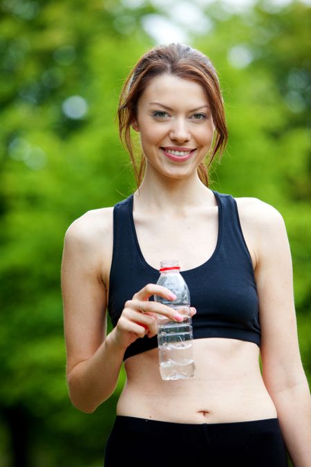 Beautiful athletic female outdoors with a bottle of water