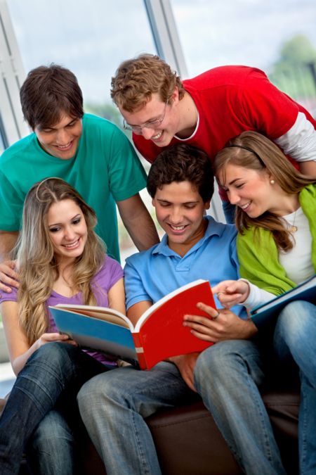 Happy group of students reading a book indoors