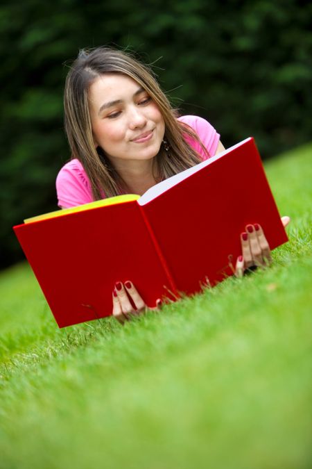 beautiful young female student reading a book outdoors