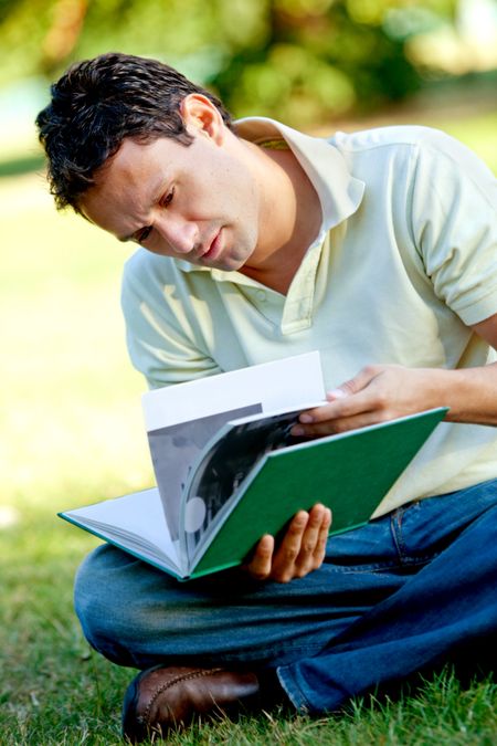 Young male student reading a book outdoors