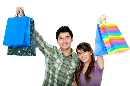 Pretty couple shopping with paper bags and arms up isolated on white