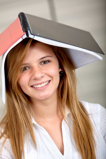 Beautiful student with a notebook on top of her head