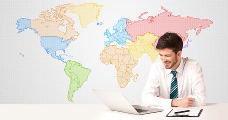 Businessman sitting at white table with colorful world map background