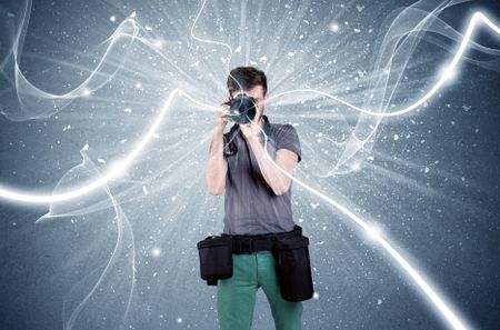 A young amateur photographer with professional photographic equipment taking picture in front of blue wall with dynamic white lines illustration concept
