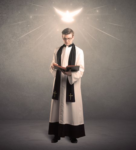 A holy priest reading a prayer from the holy bible with illustrated glowing angel above his head concept.