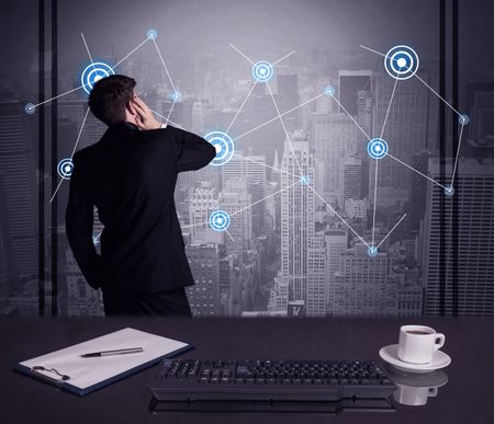 An elegant businessman connecting blue circle dots on urban city scape background concept at an office desk in a conference room