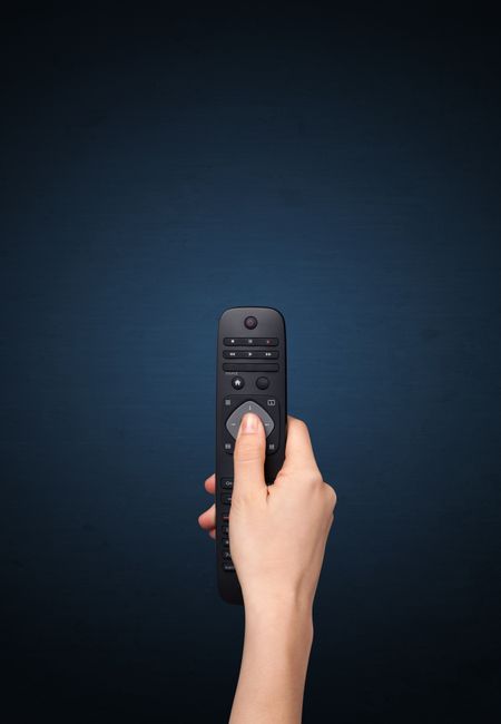 Hand holding a remote control on blue background