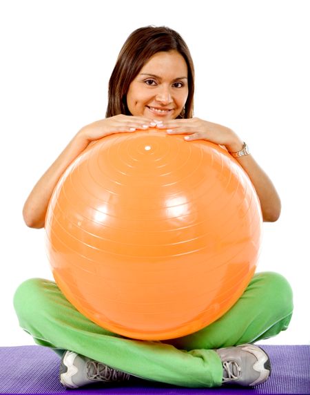 Gym woman with a pilates ball sitting on the floor isolated on white
