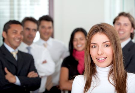 Business woman smiling at the office with her team behind her