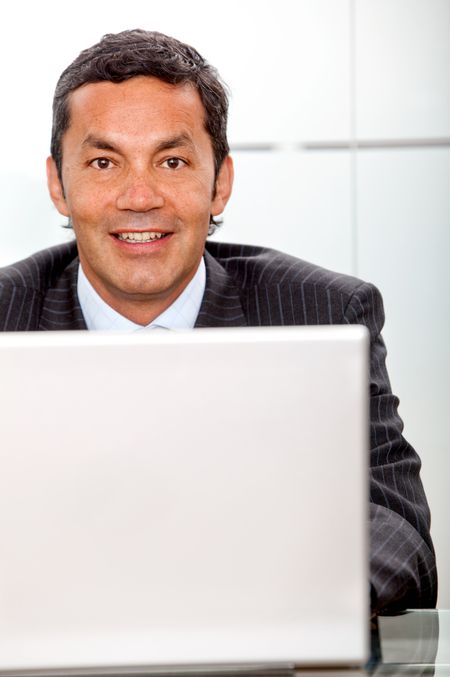 Business man at the office with a laptop and smiling