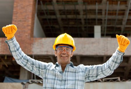 successful engineer smiling with arms up in a construction